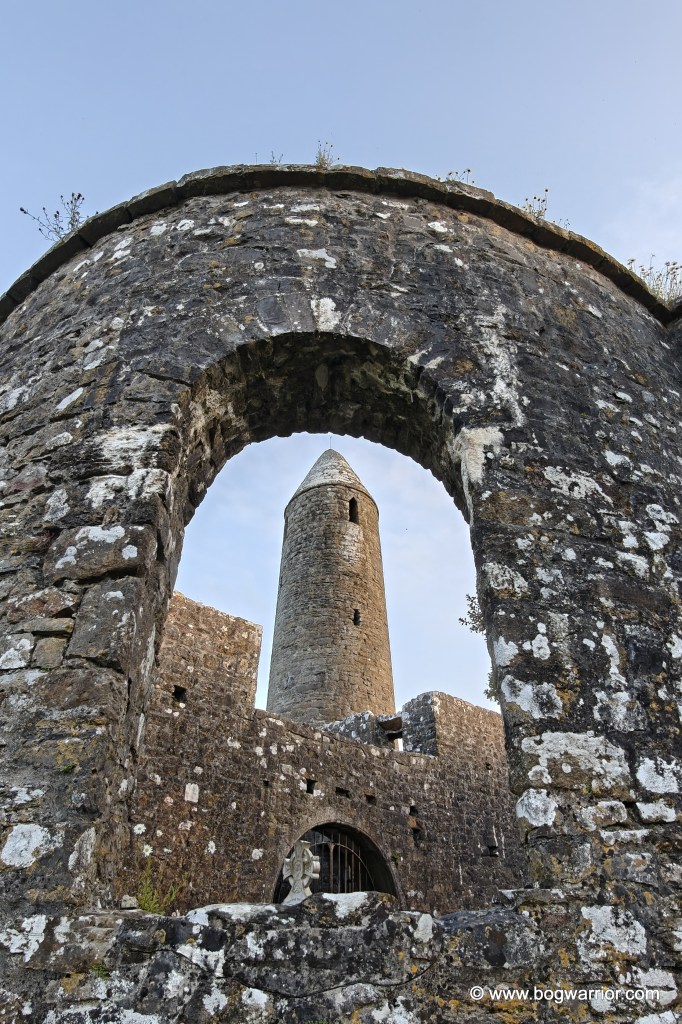 A view of Turlough Round Tower through a window in the ruined church next door